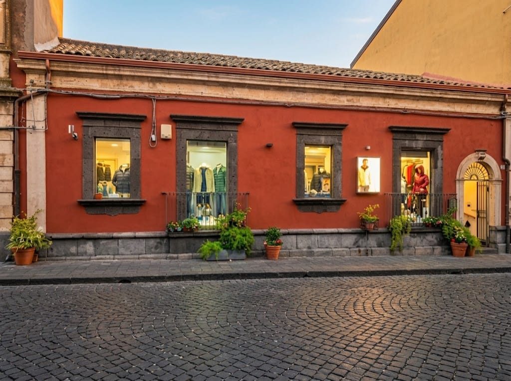 La facciata rossa del negozio Etna Style in Via Roma 129 a Linguaglossa, con le vetrine illuminate